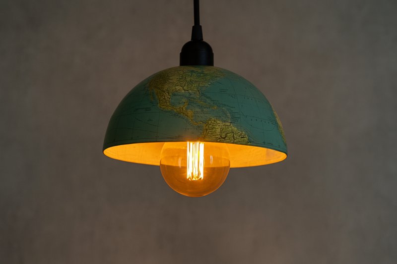 Image of a DIY pendant light cleverly crafted from half of an old world globe, with an amber Omita G95 LED Edison bulb glowing warmly from within, illuminating the continents and oceans.