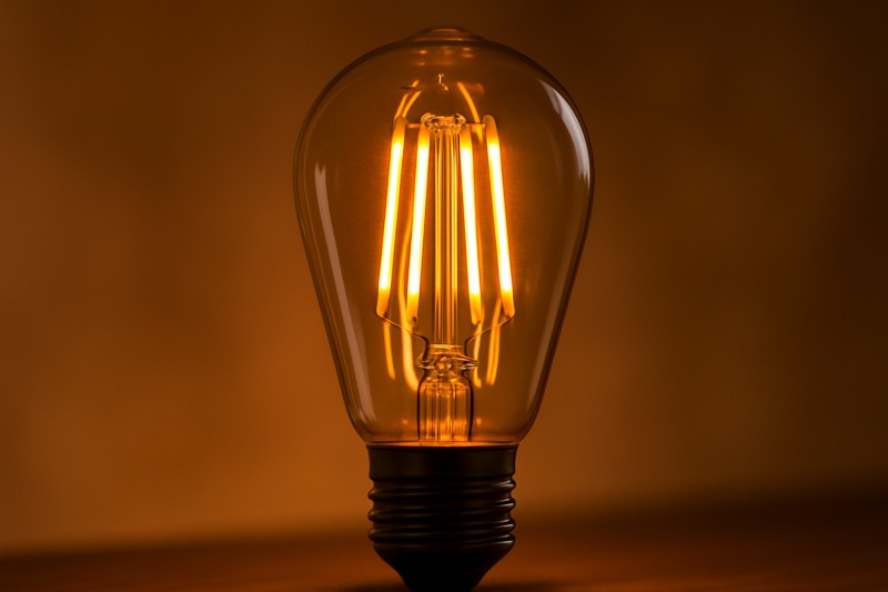 A close-up shot of an elegant LED Edison filament bulb, glowing warmly.