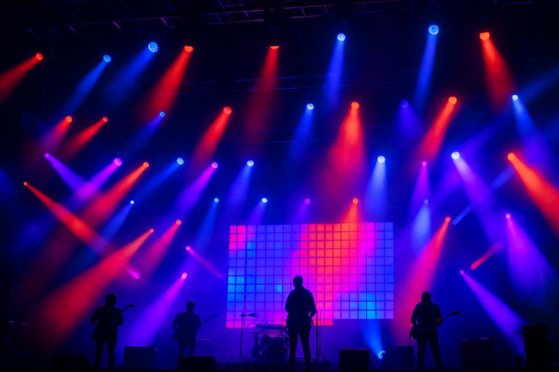 A dynamic concert stage illuminated by a complex array of colorful LED spotlights and panels