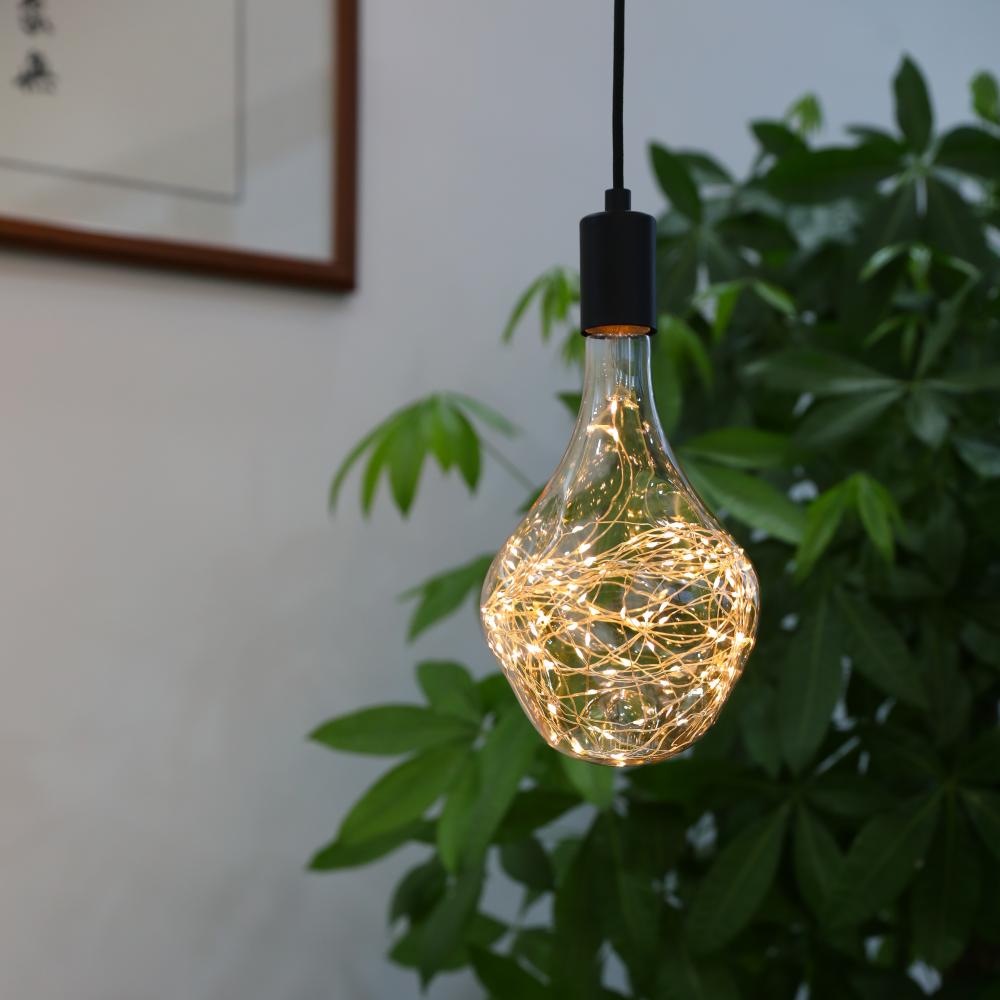 Decorative LED string light bulb hanging in a modern home interior, creating a warm ambient glow