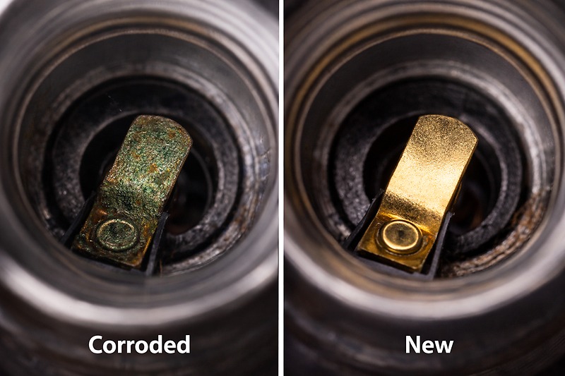 A macro photo looking up into an empty light socket. The brass tab at the bottom looks green and tarnished. A clean, shiny brass tab is shown next to it for comparison.