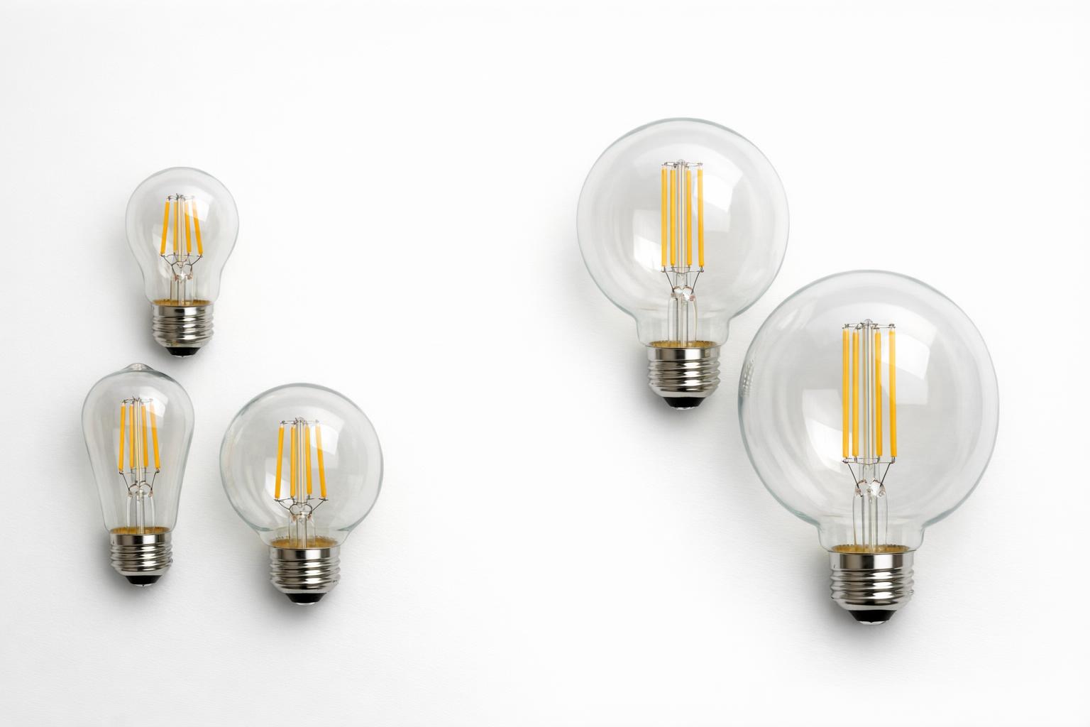 LED filament bulbs grouped by standard and large specialty glass shapes on a white table